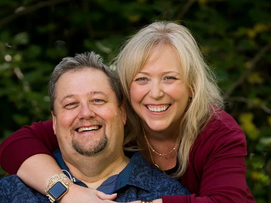 Mark and Wendy smiling in a park, Hershie in Wendy's arms